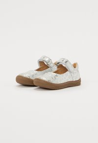 Silberne Mary Jane Schuhe für Kinder mit Blumenmuster, braunen Gummisohlen und Klettverschlüssen auf schlichtem weißen Hintergrund.