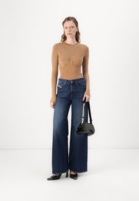  Haut marron ajusté à manches longues avec fronces, associé à un jean bleu à jambes larges. Accessoirisé avec un petit sac à main noir et des talons noirs brillants.