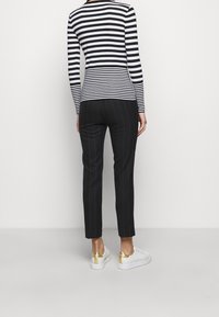 Black and white striped long-sleeve top paired with black pinstriped trousers and white sneakers featuring gold accents on the heel.