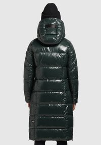 Dlhý, nadýchaný parka v tmavozelenej, lesklej látke s kapucňou, horizontálnym prešívaním a logom na chrbte.