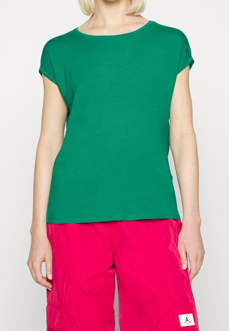 Zelené tričko s krátkým rukávem vyrobené z měkké látky, kulatý výstřih, kombinované s růžovými cargo šortkami s kapsami a nášivkou s logem.