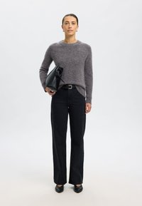 Sivi pleteni pulover, črne hlače z visokim pasom, črna usnjena torba, črni koničasti čevlji; priložnostna obleka z mehko teksturo in prilagojeno prileganje.