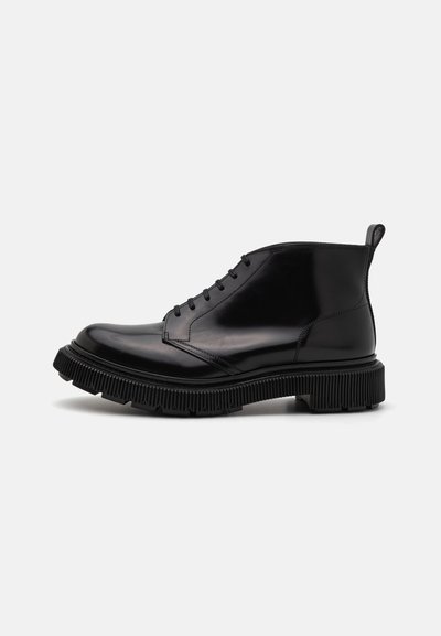 Schwarze Leder-Ankelstiefel mit einer runden Zehenform, Schnürverschluss vorne und strukturiertem Gummisohle mit markanten Rillen sowie einer Zuglasche.