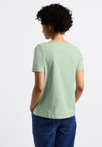T-shirt à manches courtes, vert menthe, en tissu doux, présentant une coupe décontractée, un col rond et des détails de couture subtils.
