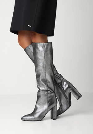 Bottes argentées métalliques jusqu'aux genoux avec une finition texturée, un bout pointu et un talon épais, dotées d'une fermeture éclair sur le côté.