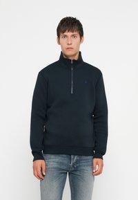 Sweat à col haut en polaire marine avec fermeture zippée quart. Caractéristiques : poignets et ourlet côtelés, ainsi qu'un logo discret sur la poitrine.
