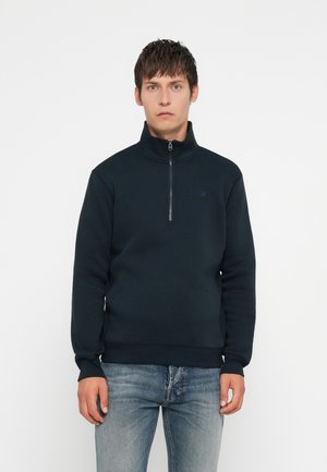 Navy fleece sweatshirt with a high collar and quarter-zip closure. Features ribbed cuffs and hem, and subtle logo detail on the chest.