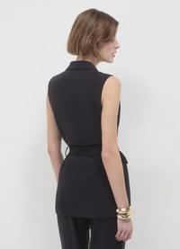 Top nero senza maniche con colletto, vita aderente e texture liscia. Presenta un taglio dritto e dettagli di design minimi.