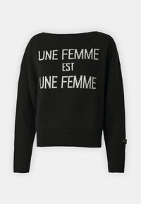Maglione nero a maglia con scollo ampio e polsini a coste. Presenta il testo bianco: "UNE FEMME EST UNE FEMME" in evidenza. Taglio corto.