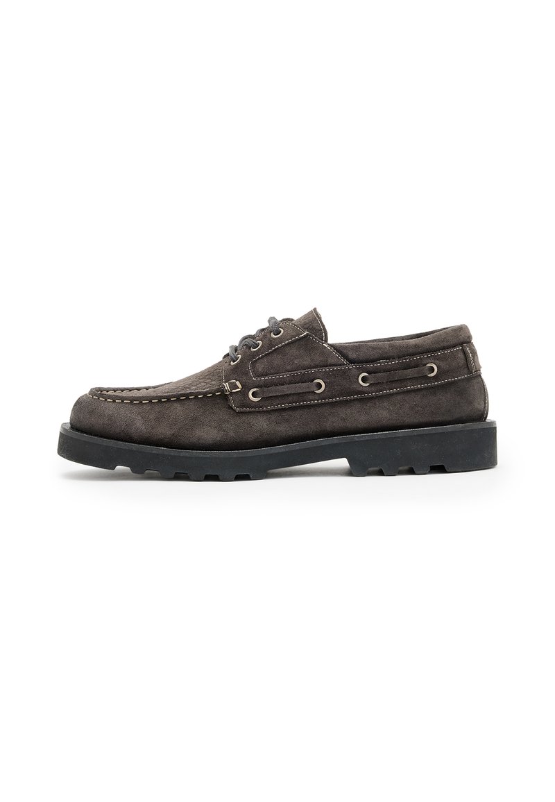 Scarpe da barca in suede grigio scuro con profilo basso, cuciture bianche, occhielli in metallo e suola in gomma nera texturizzata.