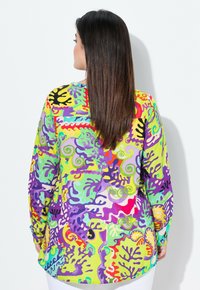 Blouse met lange mouwen, voorzien van een levendig, multicultureel abstract patroon met groene, paarse, rode en gele tinten op een lichtgewicht stof.