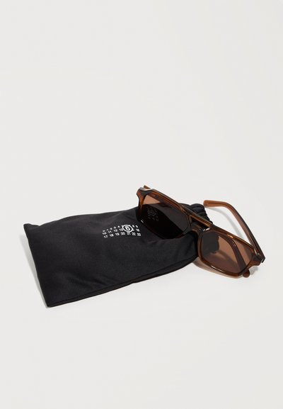Brown rectangular sunglasses resting on a black soft pouch with white printed numbers on a plain light background.