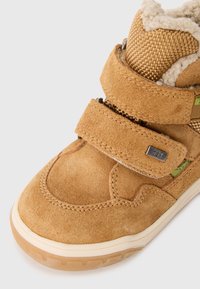 Helle Wildleder High-Top Sneaker mit einem strukturierten Mesh-Kragen, zwei Klettverschlüssen und einer Gummisohle mit dezentem Profil.