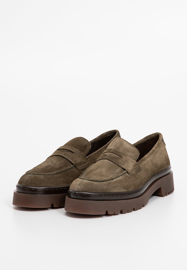 Mocassini in suede verde oliva con punta rotonda, dettagli cuciti e suola spessa in gomma marrone. Design slip-on con tacco basso.