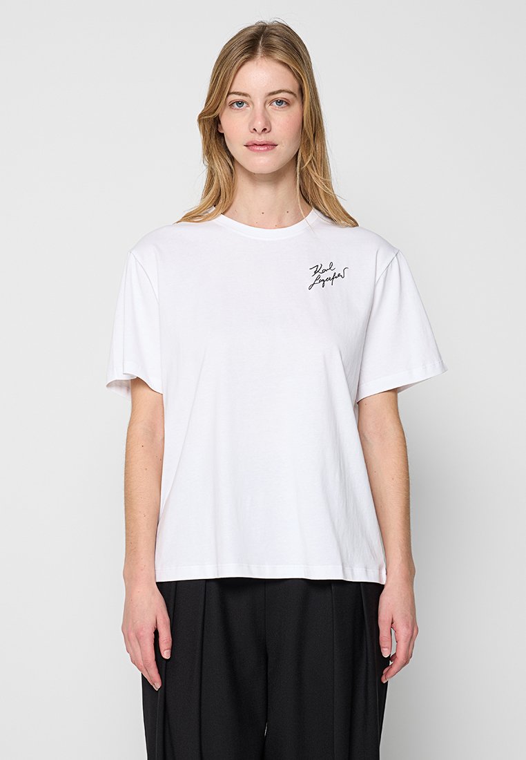 Weißes Baumwoll-T-Shirt mit lockerem Schnitt, Rundhalsausschnitt und kurzen Ärmeln. Auffälliges schwarzes signiertes Logo auf der linken Brustseite.