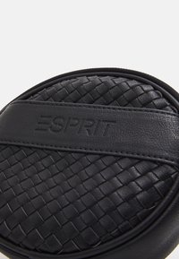 Černá kožená taška s tkanou strukturou na přední straně, se vzorkem embosovaného loga "ESPRIT" a zaobleným tvarem.