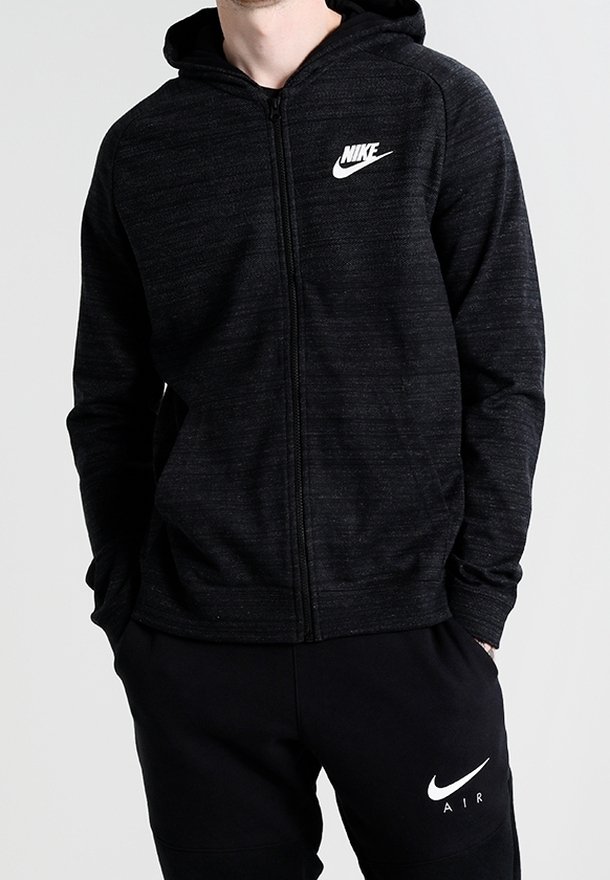 Svart zip-up hoodie gjord av texturerat tyg med huva. Har en vit Nike-logga på vänster bröst och kontrasterande svarta träningbyxor med logga.