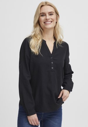 Svart långärmad topp med V-ringning, fem knappar och mjukt texturerat tyg. Matcher med blå denimjeans.