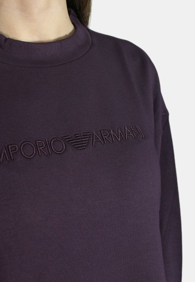 Felpa viola con collo alto, caratterizzata da un logo ricamato "Emporio Armani" dello stesso colore. Tessuto morbido e liscio.
