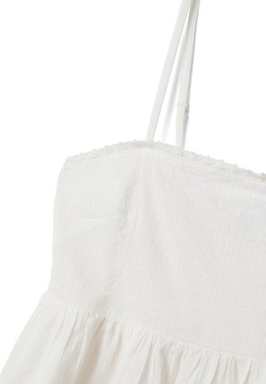 Witte mouwloze jurk met dunne verstelbare bandjes, gestructureerde stof en een gerimpelde zoom aan de onderkant.