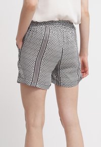 Černé a bílé vzorované šortky s elastickým pasem, s bočními kapsami a vertikálními pruhy. Lehce strukturovaná tkanina.