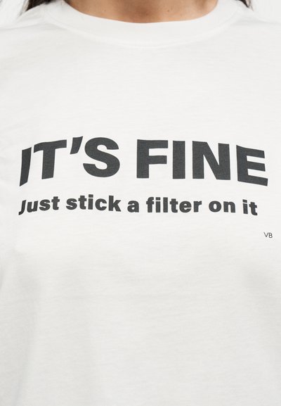 Λευκό βαμβακερό t-shirt με έντονο μαύρο κείμενο που γράφει «ΕΙΝΑΙ ΕΝΤΑΞΕΙ» και «Απλώς βάλ' του ένα φίλτρο.» Απλός σχεδιασμός με στρογγυλή λαιμόκοψη.