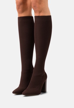 Bruine geribde kniehoog boots met een spitse neus en een gestapeld hak, gemaakt van textiel dat de been omarmt.