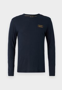 Jūrinio stiliaus ilgomis rankovėmis marškinėliai pagaminti iš medvilnės, su apvaliu kaklu ir mažu auksiniu logotipu viršutinėje kairėje krūtinės pusėje. Lygi tekstūra.