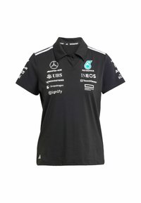 Černé polo tričko s klasickým límcem, má bílé pruhy na ramenou, několik log sponsorů a malé logo na lemu.