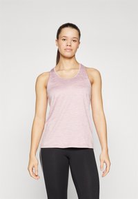 Heled roosa, ilma varrukateta sportlik tank top, mis on valmistatud tekstuurilisest kangast; sellel on ümar kaelus ja lahtine lõige, koos mustade retuusidega.