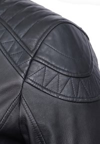 Ärmel einer schwarzen Lederjacke mit gesteppten Details, glatter Textur, abgerundeter Schulter mit genähten Akzenten und dezenten, dreieckigen Mustern.