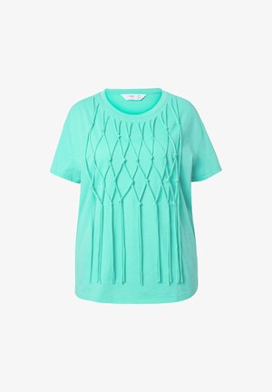 La camiseta de manga corta en verde menta presenta un diseño texturizado con acentos anudados y largas hebras de tela que crean un patrón decorativo.