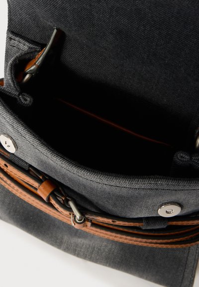 Saco de tela cinza escuro com alça de couro castanho e ferragens prateadas. Bolsa interna visível e tecido suave e texturizado. Design de topo aberto.