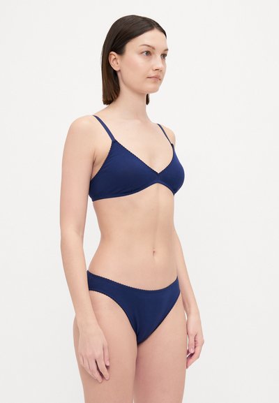 Navy blue bikini set featuring a triangle bralette with thin straps and scalloped edges, paired with low-rise bikini bottoms with similar detailing.