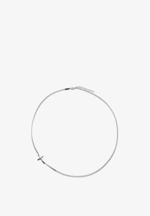 Sølvkjedet halskjede med et lite polert korsanheng plassert asymmetrisk på en hvit bakgrunn.