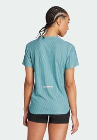 Chemise pour femme à manches courtes, texturée, en teal avec des rayures verticales, dotée d'un dos en scoop et d'un détail réfléchissant près de l'ourlet.