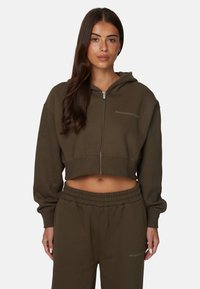 Sweat à capuche zippé, cropped, en mélange de coton vert olive. Doté d'une capuche avec cordon de serrage et d'un logo brodé sur la poitrine. Associé à un pantalon de survêtement assorti.