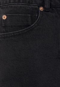 Black denim fabric with a smooth texture. Features a small front pocket and copper-colored metal rivet, with subtle diagonal weaving pattern.