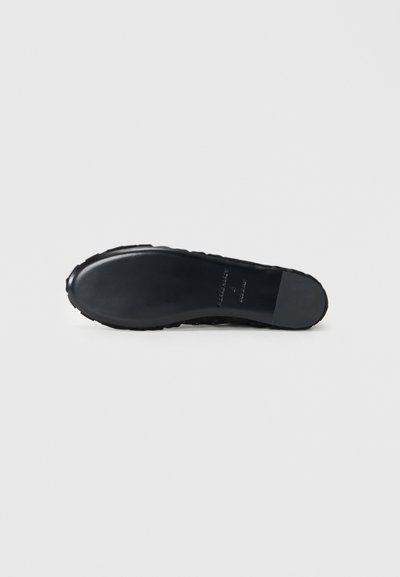 Black rubber shoe sole featuring a textured bottom with traction patterns and subtle branding embossed on the side.