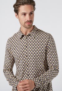 Langarmshirt in een meerkleurig patroon van blauwe, gele en zwarte ovalen; heeft een knoopsluiting aan de voorkant en een klassieke kraag.