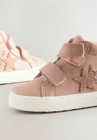 Chaussures en cuir rose avec deux bandes Velcro, ornées d'une étoile scintillante sur le côté et d'une semelle en caoutchouc blanc texturé.
