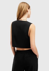 Schwarzes Crop-Top mit sauberem Ausschnitt und ärmellosem Design. Verfügt über eine glatte Textur, eine figurbetonte Form und wird mit lässigen schwarzen Hosen kombiniert.
