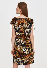 Blumenmuster-Kleid mit schwarzem Hintergrund, kurzen Ärmeln mit Bindebändern und einem elastischen Taillenbund, der eine lässige Silhouette betont.