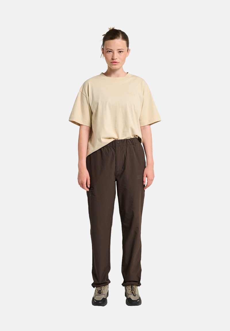 Beige katoenen t-shirt met een relaxed fit, gecombineerd met bruine elastische broek met zakken. Schoeisel is grijs en zwart met een robuust ontwerp.