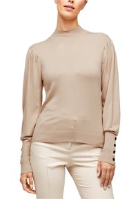 Beżowy sweter z długim rękawem i wysokim dekoltem, z prążkowanymi mankietami z ciemnymi guzikami oraz lekko puffed designem na ramionach.