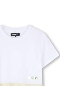 Biała bawełniana koszulka z krótkim rękawem, z metalicznym logo DKNY na dolnym ściągaczu i gładką teksturą. Prosty, casualowy design.