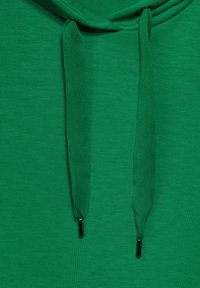 Zelená mikina s kapucí vyrobená z měkké látky, s přední kapsou, stahovací kapucí s texturovanými šňůrkami a hladkým, jednolitým povrchem.