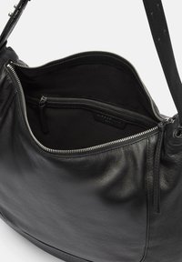 Sac à main en cuir noir avec un haut zippé, présentant une texture douce et une poche intérieure. L'intérieur est doublé de tissu noir.