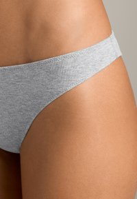 Slip bikini grigio a coste con una fascia larga in vita, caratterizzato da una texture liscia e un design a copertura minima, mostrato su uno sfondo neutro.