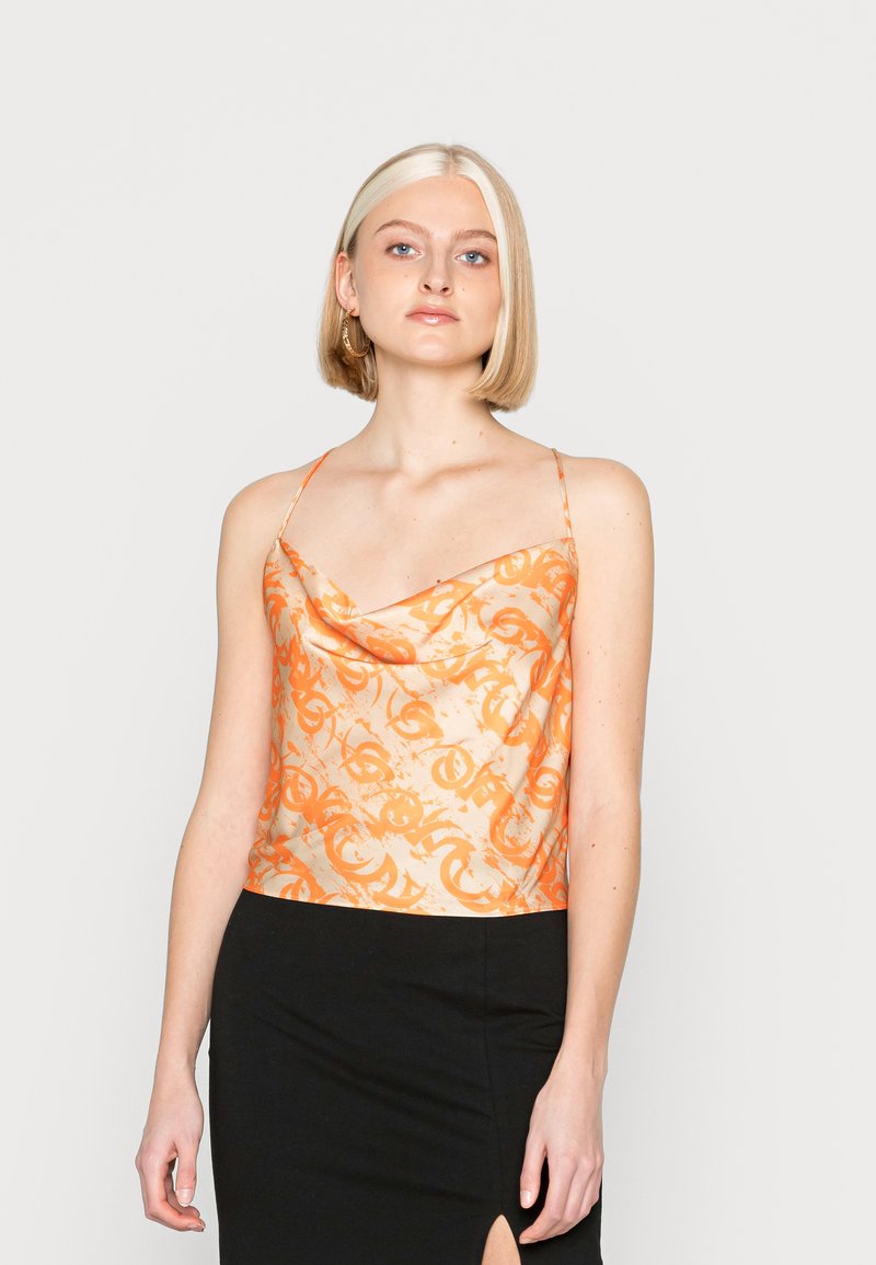 Top de cetim com decote drapeado e padrão abstrato em laranja, alças finas e ajustáveis, com barra reta, combinado com uma saia preta. Textura suave.